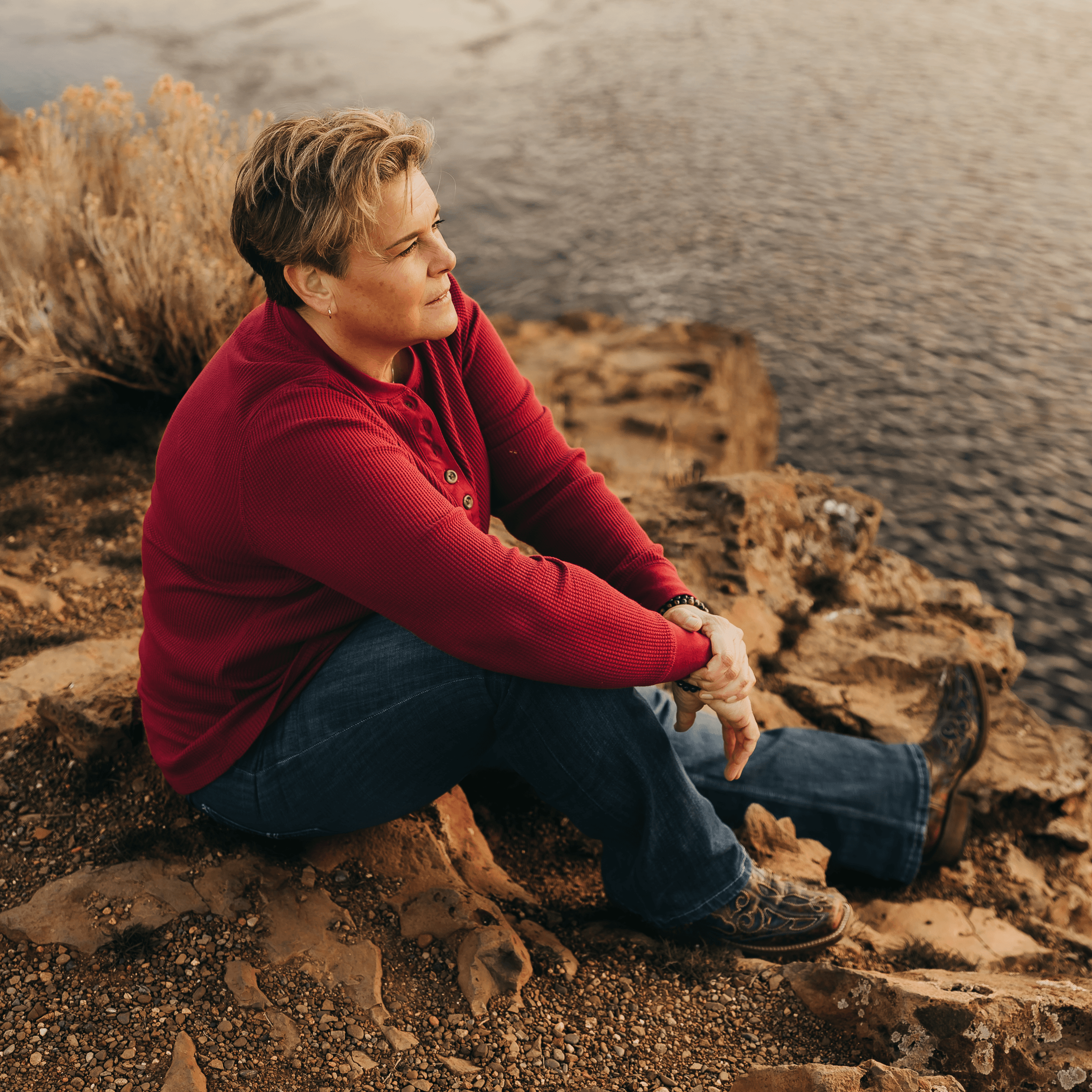 Jen Huber sitting on a rocky overlook by the water